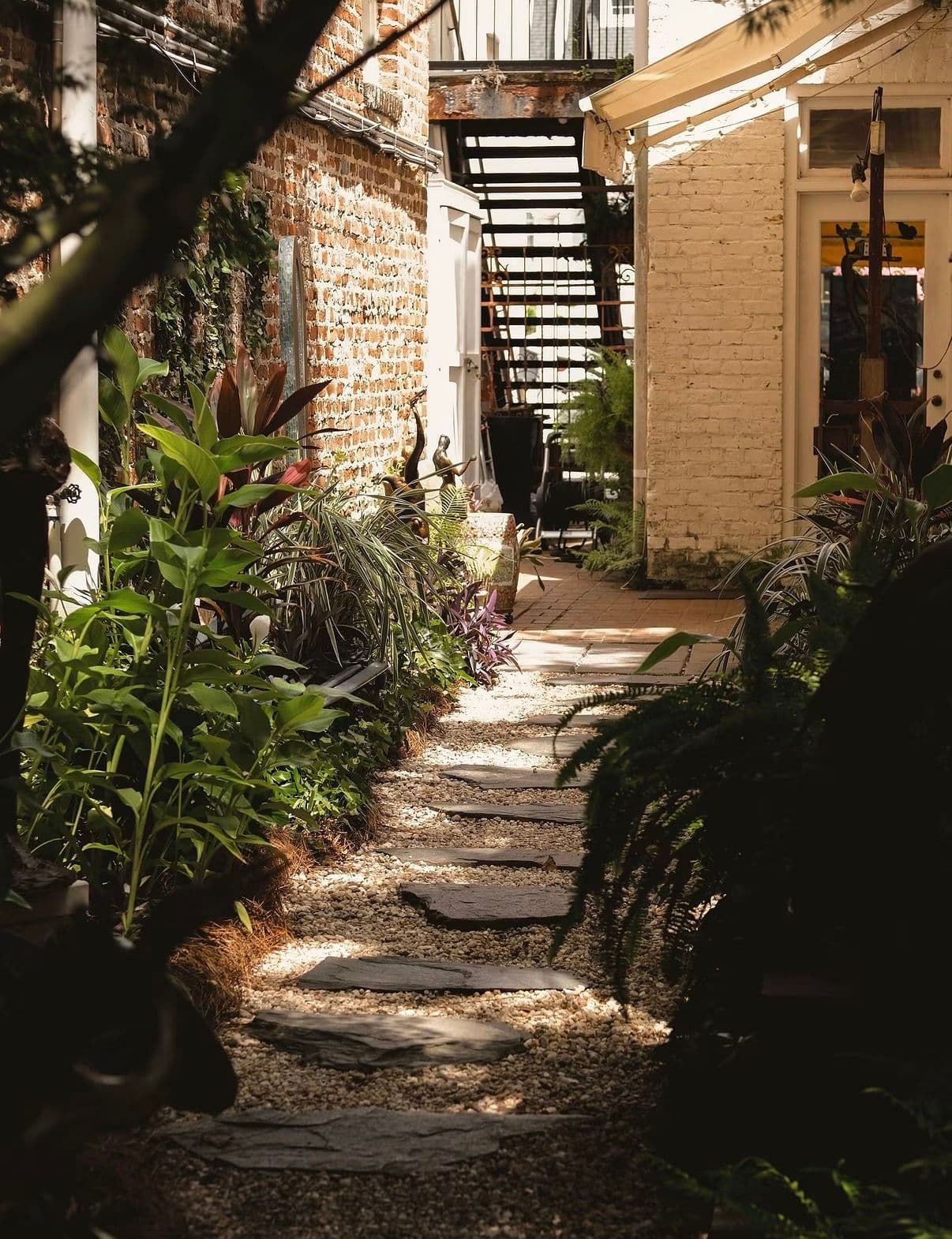 A stepping-stone path through a green courtyard between old brick buildings in Charleston