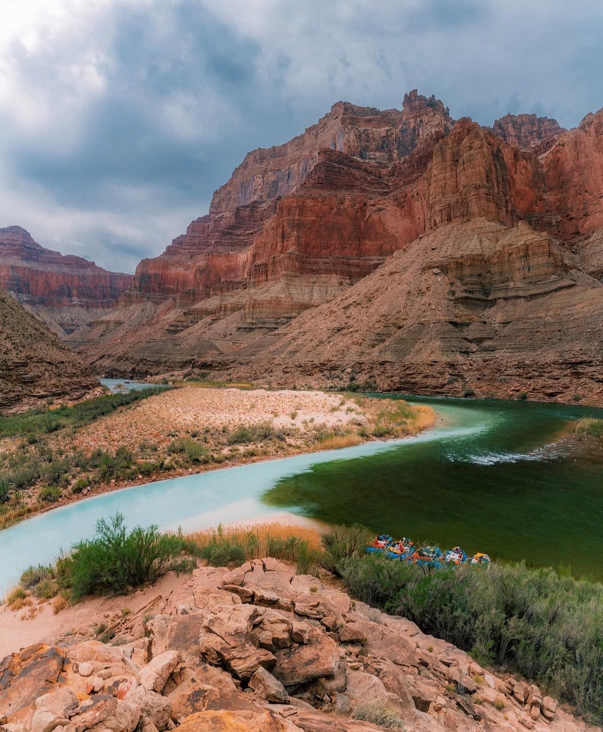 The turquoise Colorado River bending below layered canyon cliffs