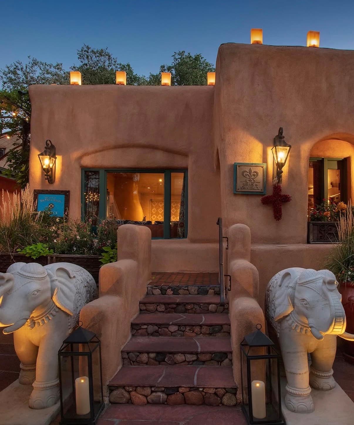 An adobe entrance lit by lanterns at dusk