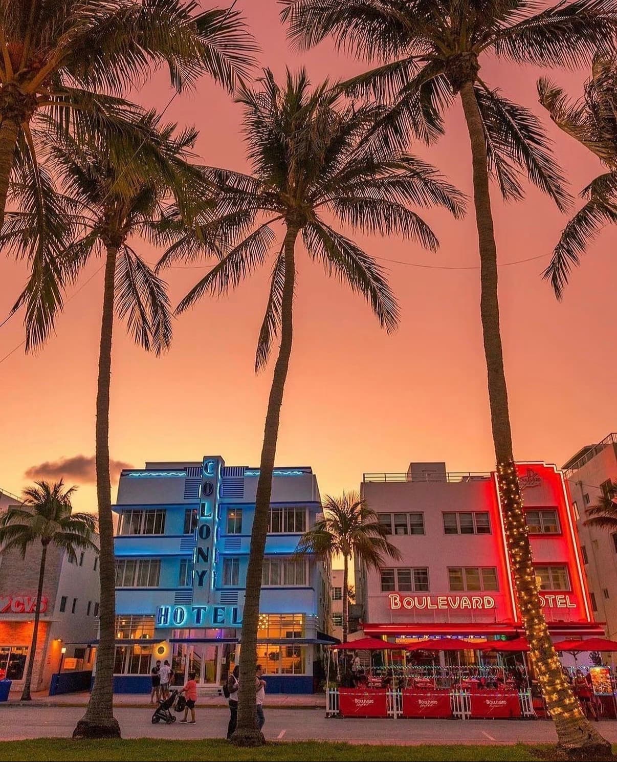 Palms and neon-lit Art Deco hotels on Ocean Drive under a pink sky
