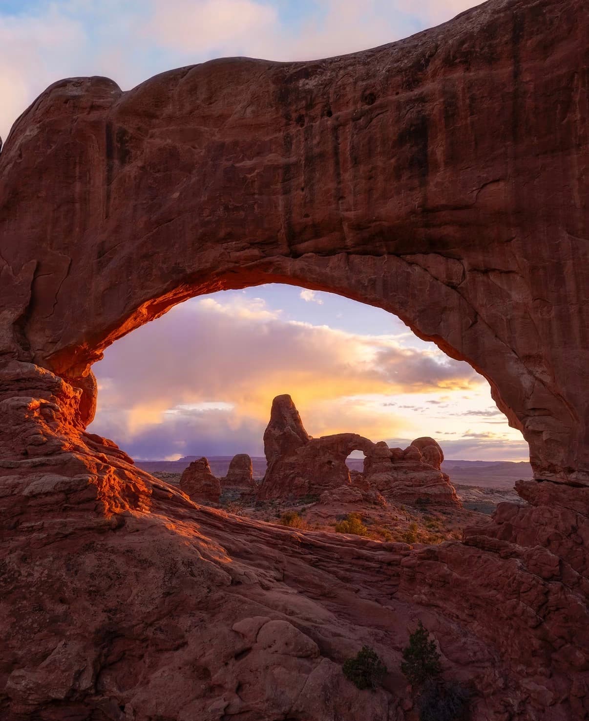 A sandstone window framing Turret Arch at sunset