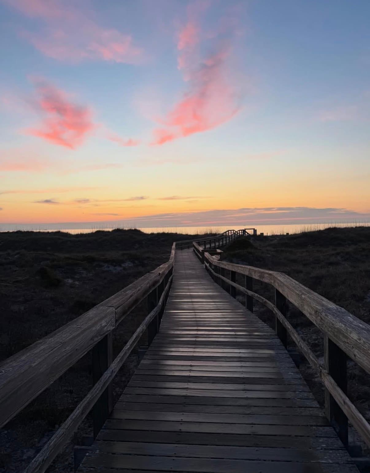 A boardwalk over the dunes at sunset