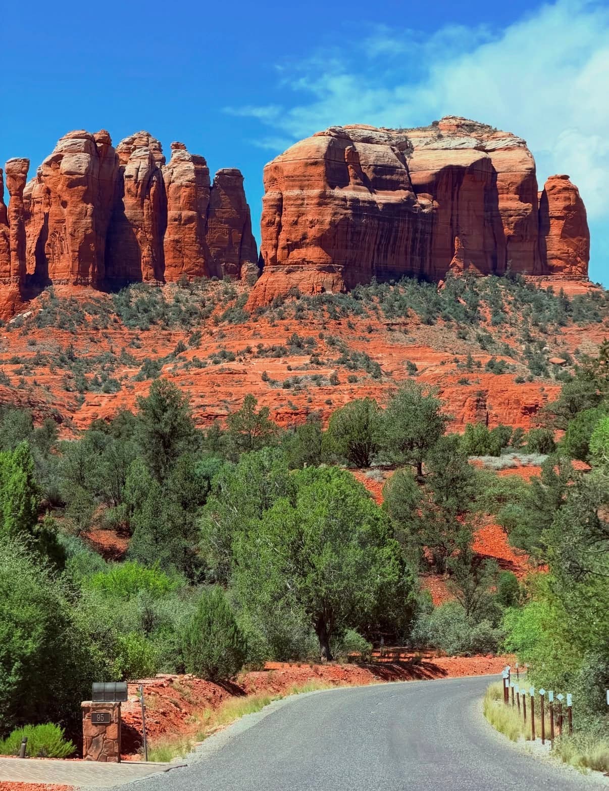 Red sandstone spires of Cathedral Rock above green scrub and a winding road