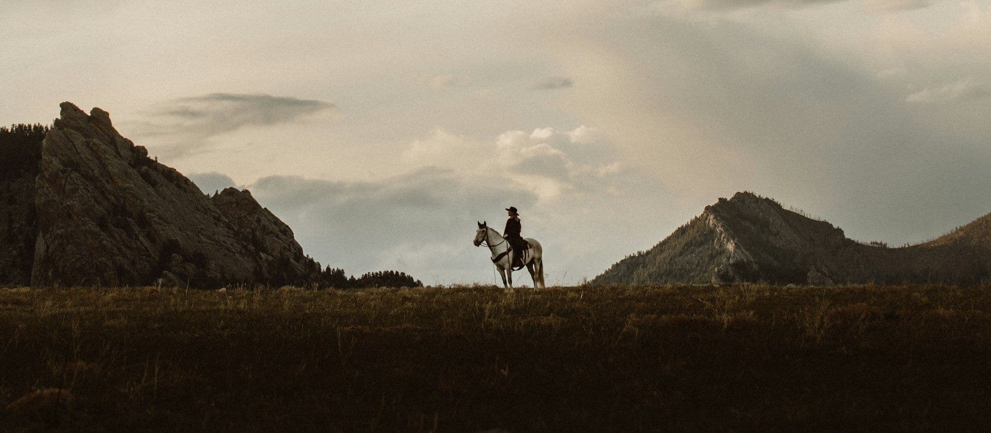 A lone rider on a ridge against a wide evening sky
