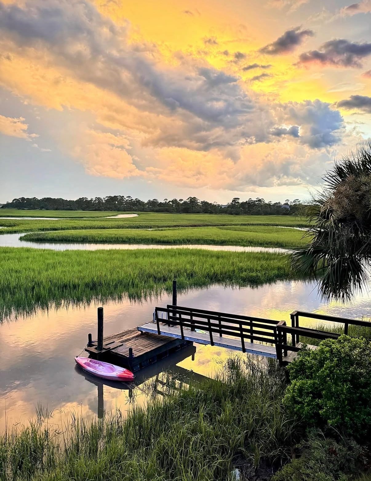 A small dock on a tidal marsh creek under a golden sky