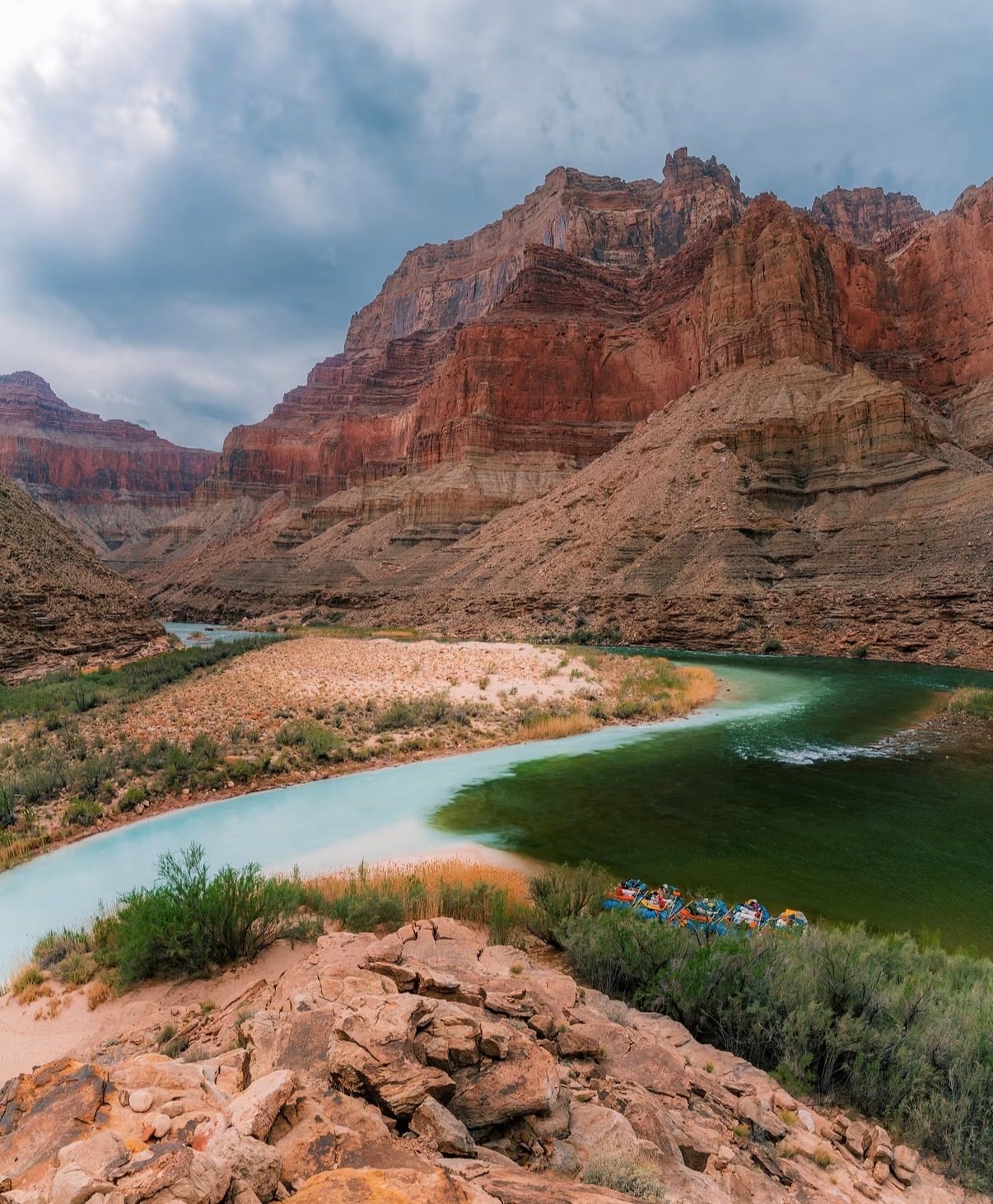 The turquoise Colorado River bending below layered canyon cliffs