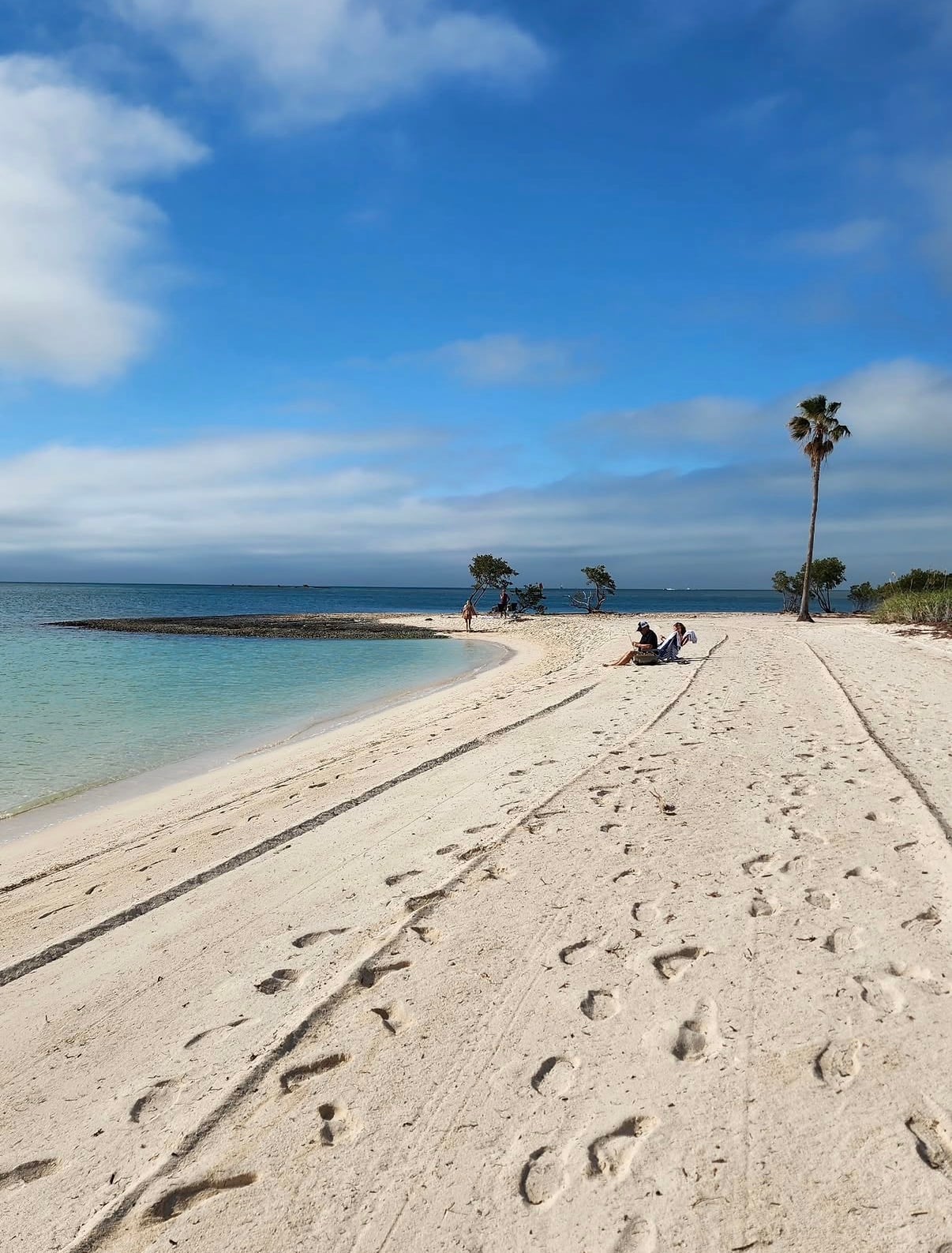 A white sandbar curving into clear shallow water