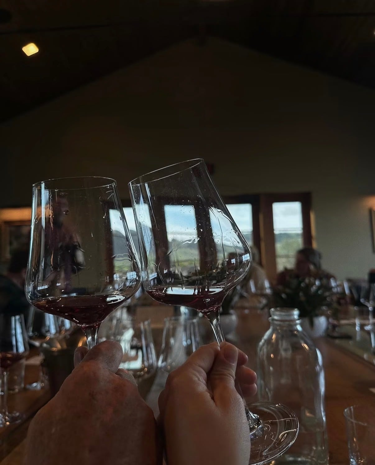 Two glasses of red wine raised in a winery tasting room