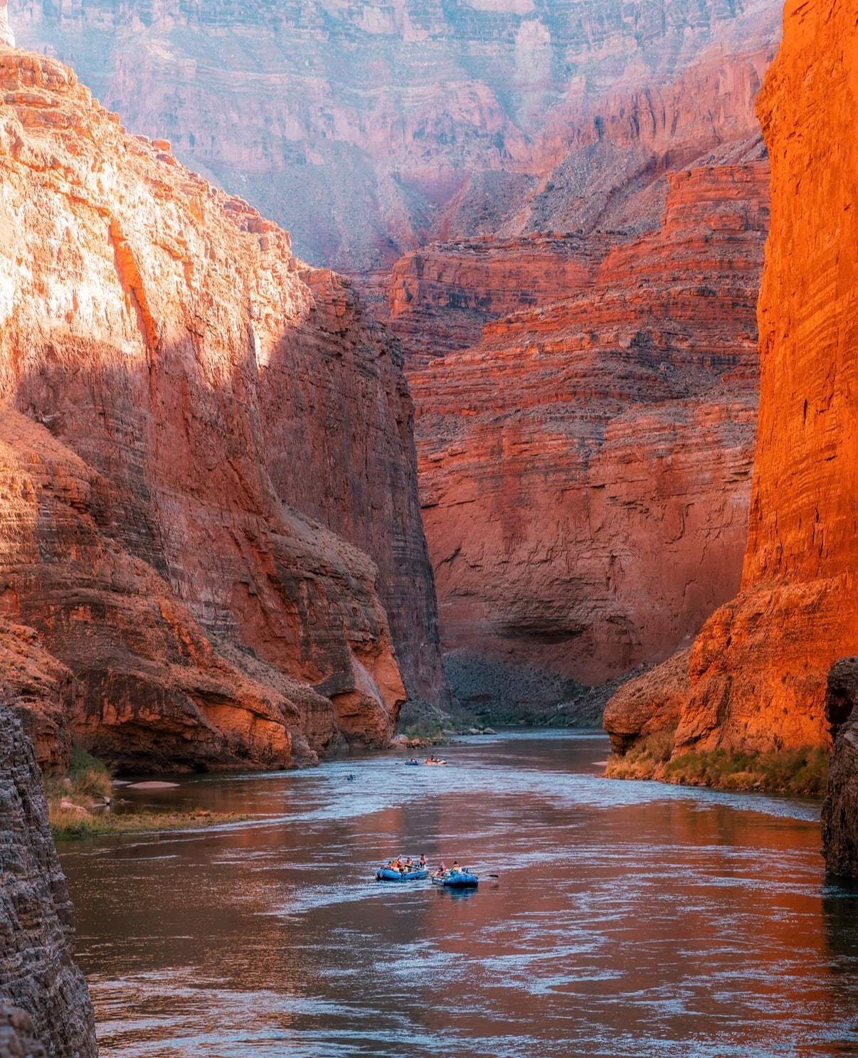 Rafts on the river between towering red canyon walls