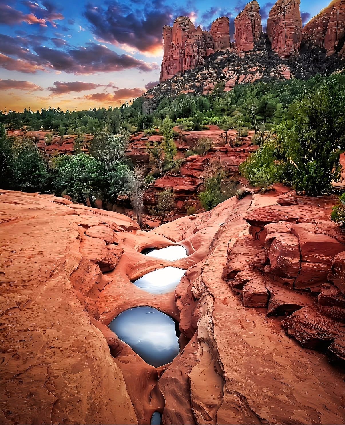 Rain pools in red slickrock below Cathedral Rock at sunset