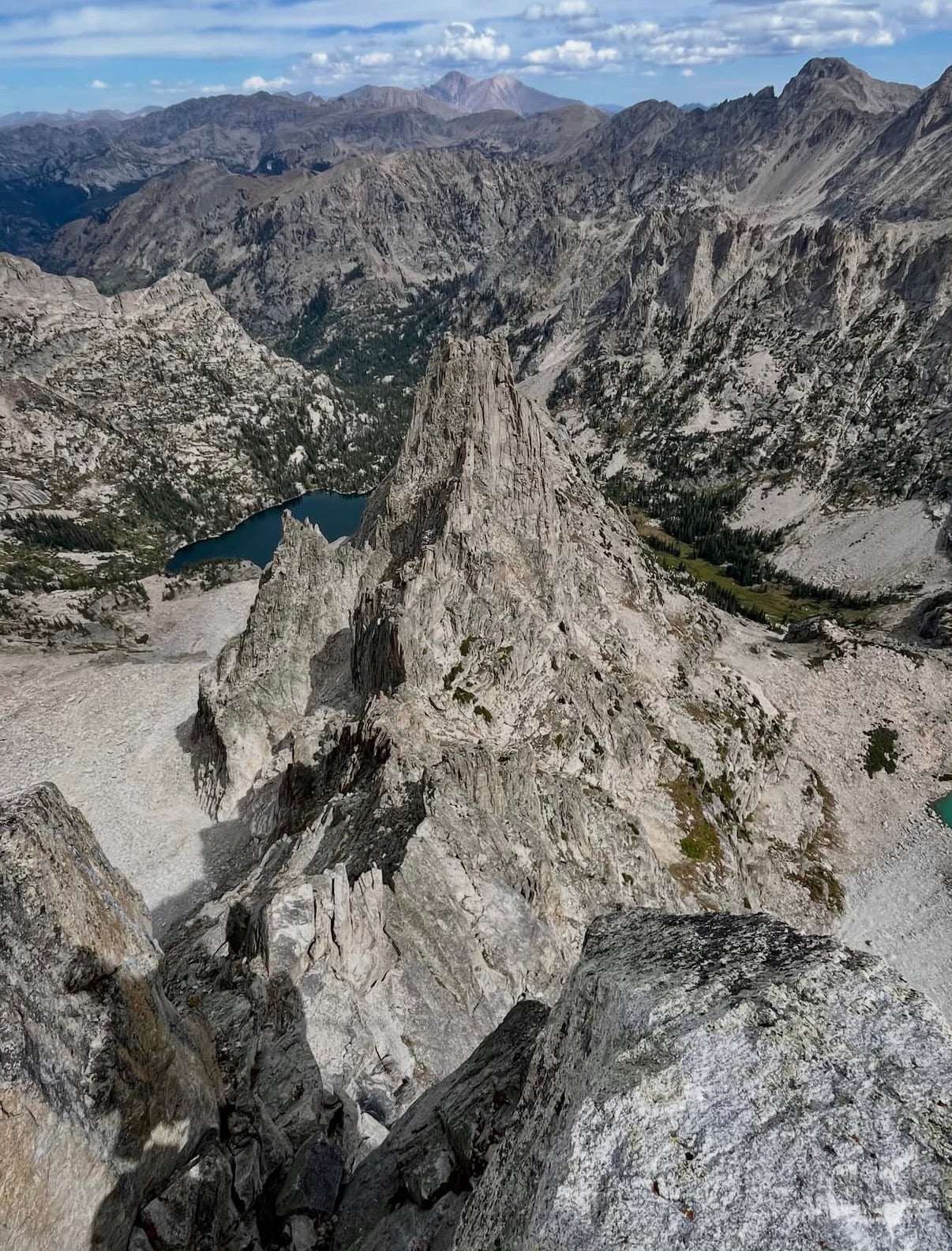 A jagged granite spire above alpine lakes and high peaks