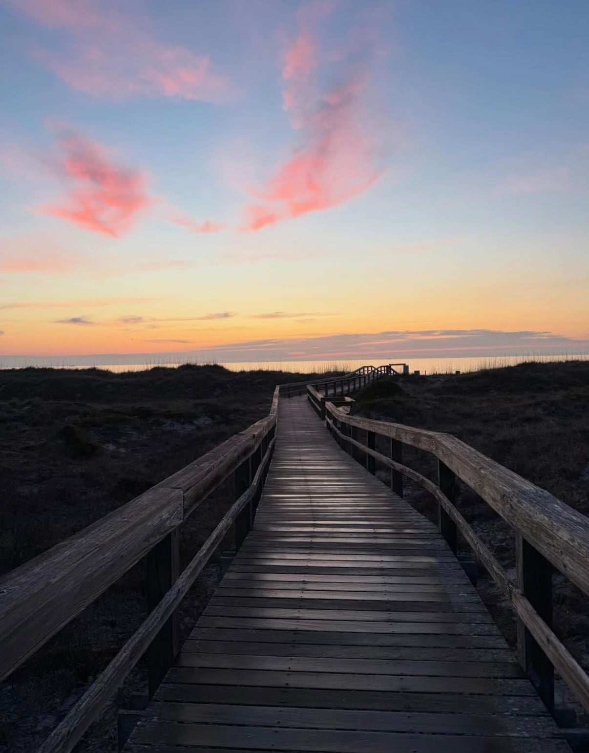 A boardwalk over the dunes at sunset