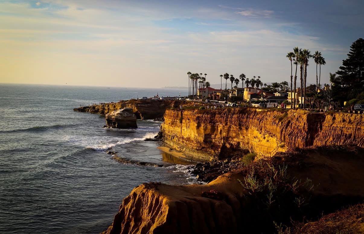 Golden sandstone cliffs and palms along the Pacific at late afternoon