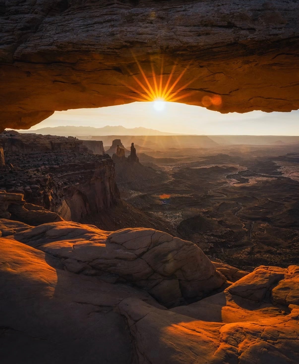 Sunrise bursting under Mesa Arch above deep canyon country