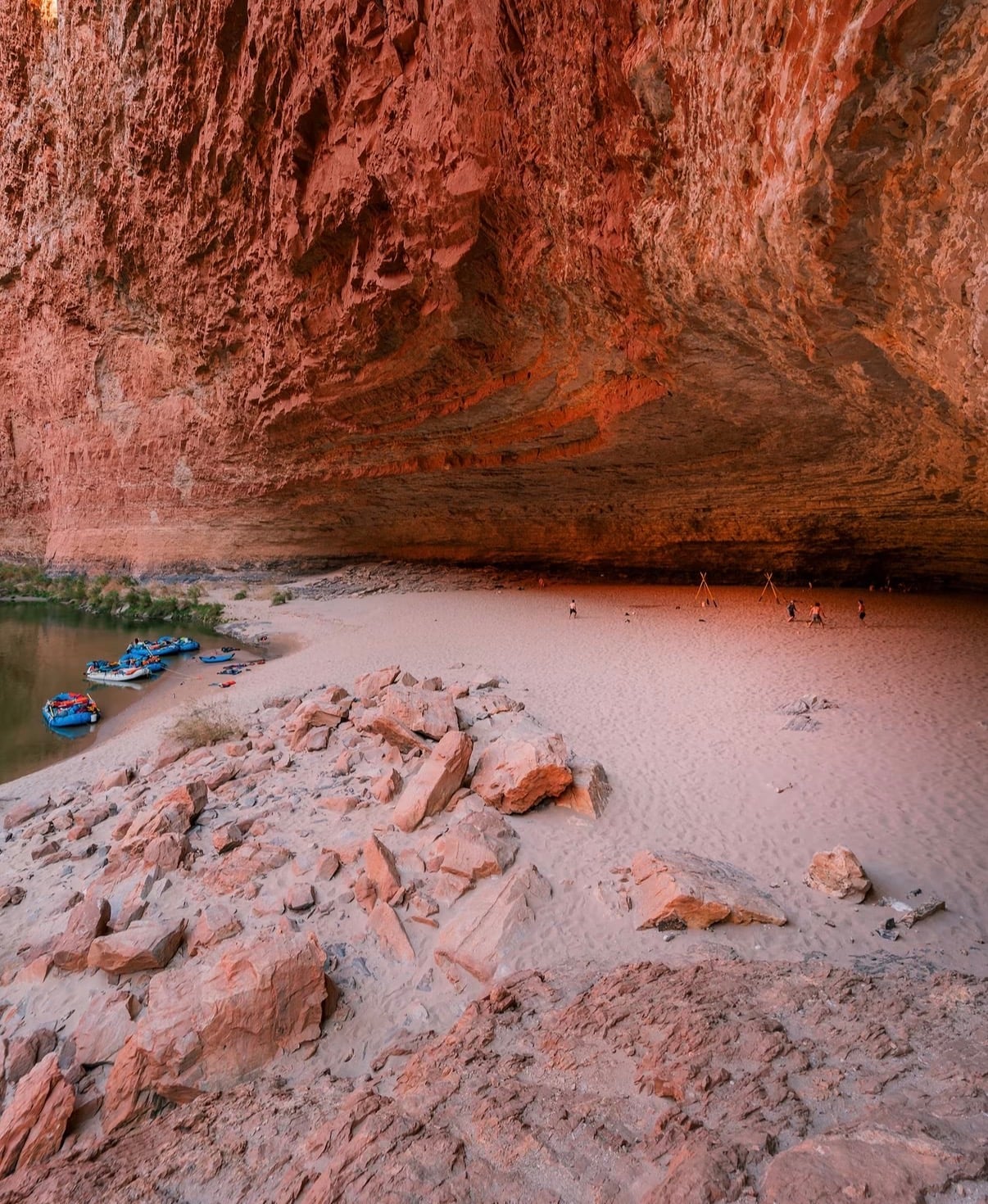 A vast sandstone overhang above a sandy river beach