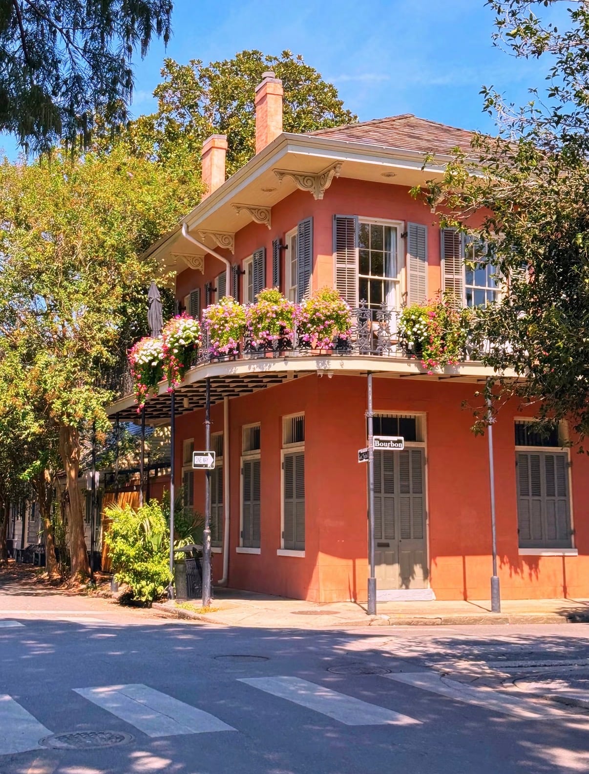 A coral-pink Creole corner house with a flower-hung iron balcony