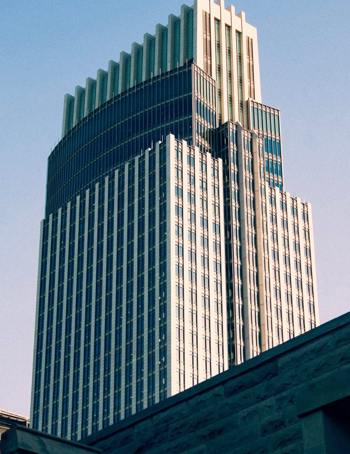 A downtown Omaha tower with a glass crown against a clear sky