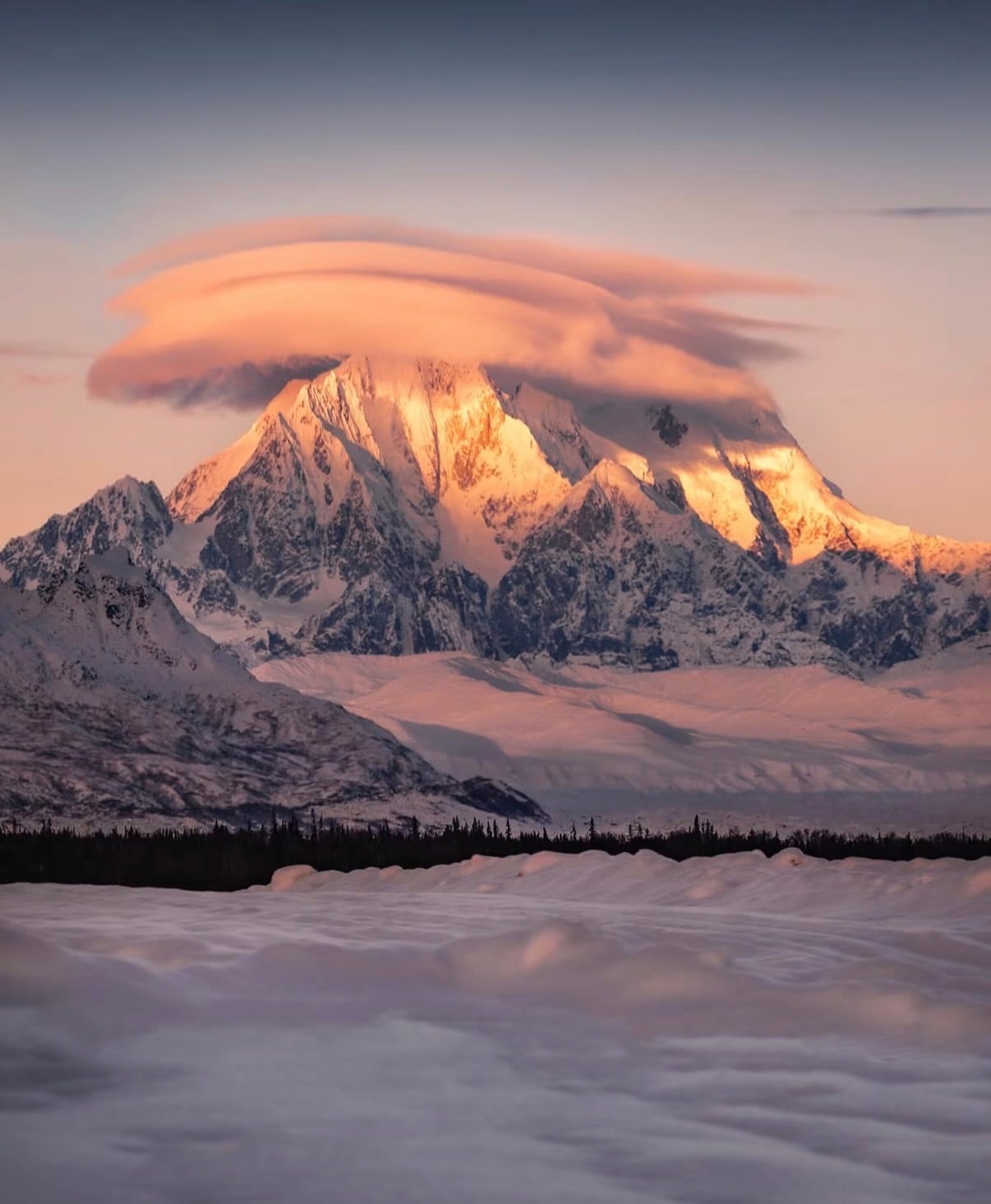 A snow-covered Alaska peak under a lenticular cloud at sunset