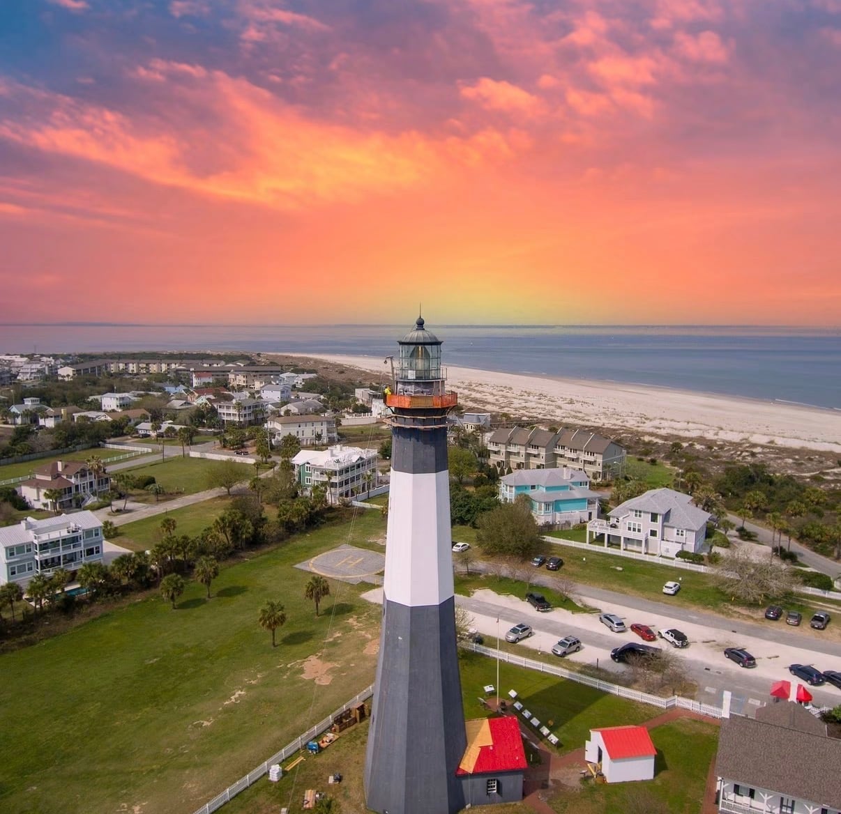 The Tybee Island lighthouse above beach houses at a pink sunset