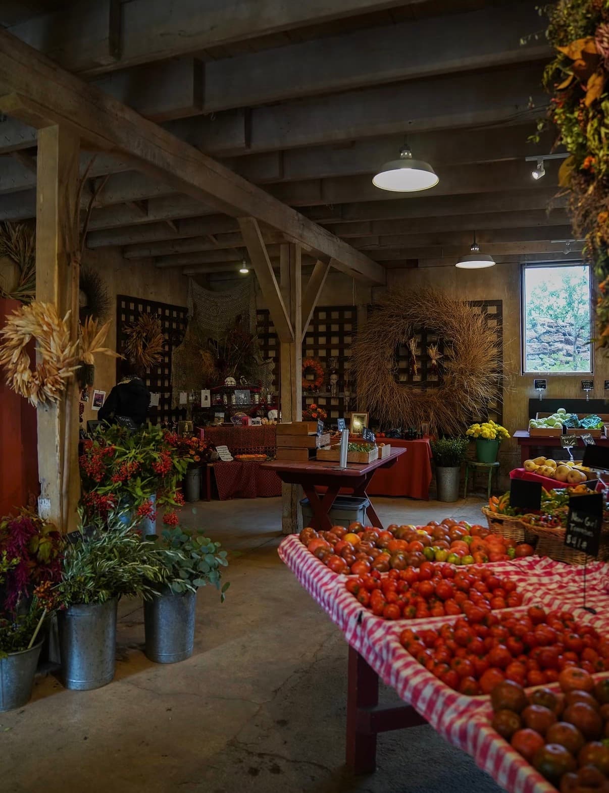 A farm barn with tables of heirloom tomatoes, flowers and harvest wreaths